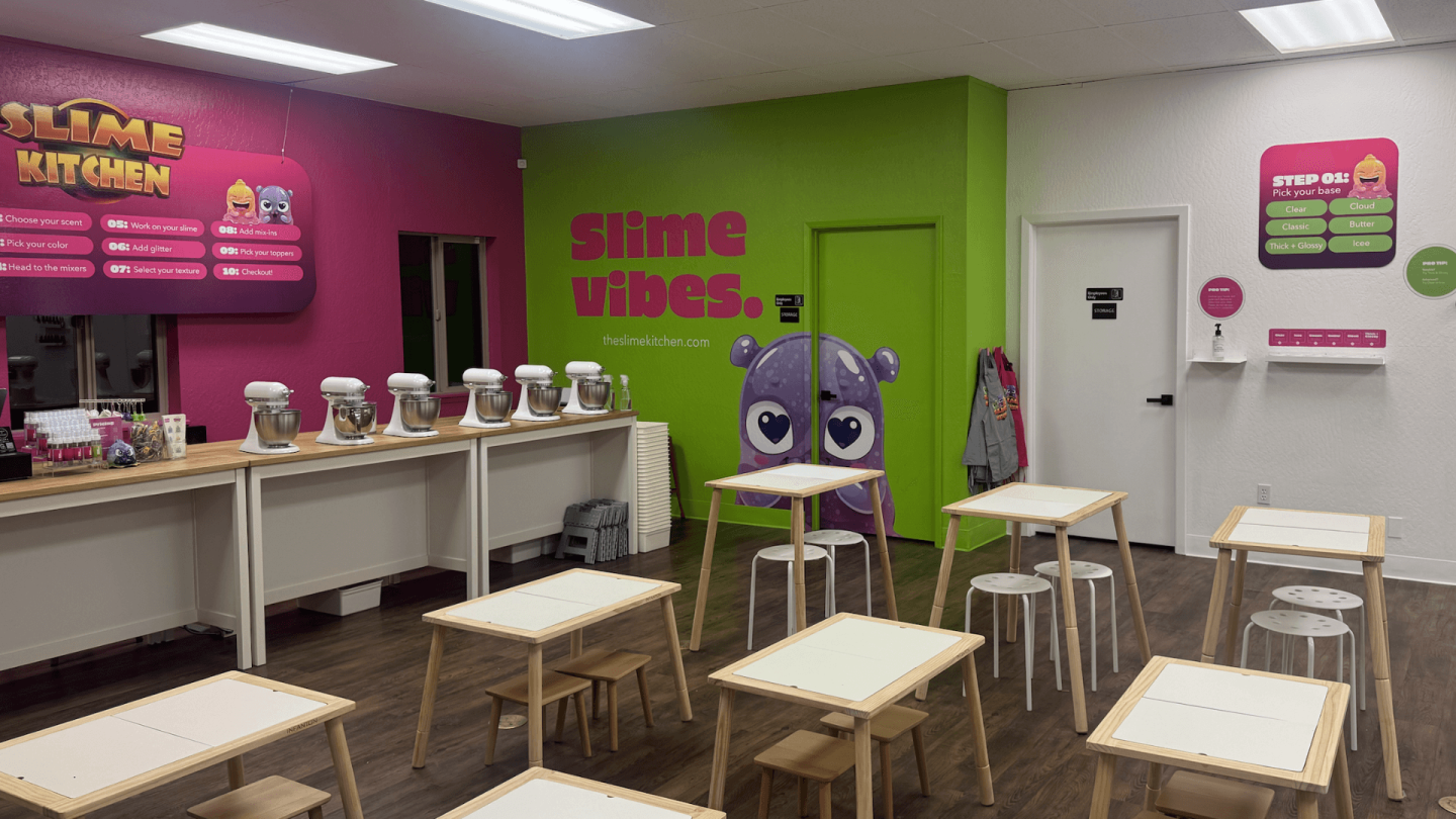 Bright slime shop with colorful walls and tables, stools, and slime jars displayed.