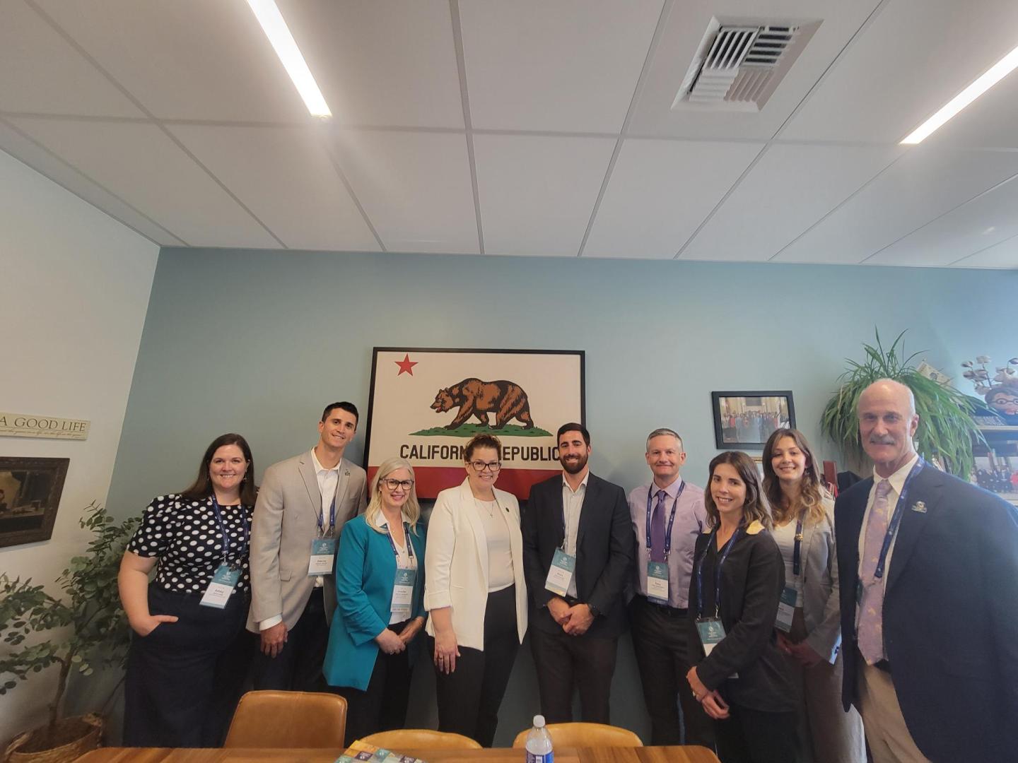Group of people smiling in an office under a California-themed artwork.