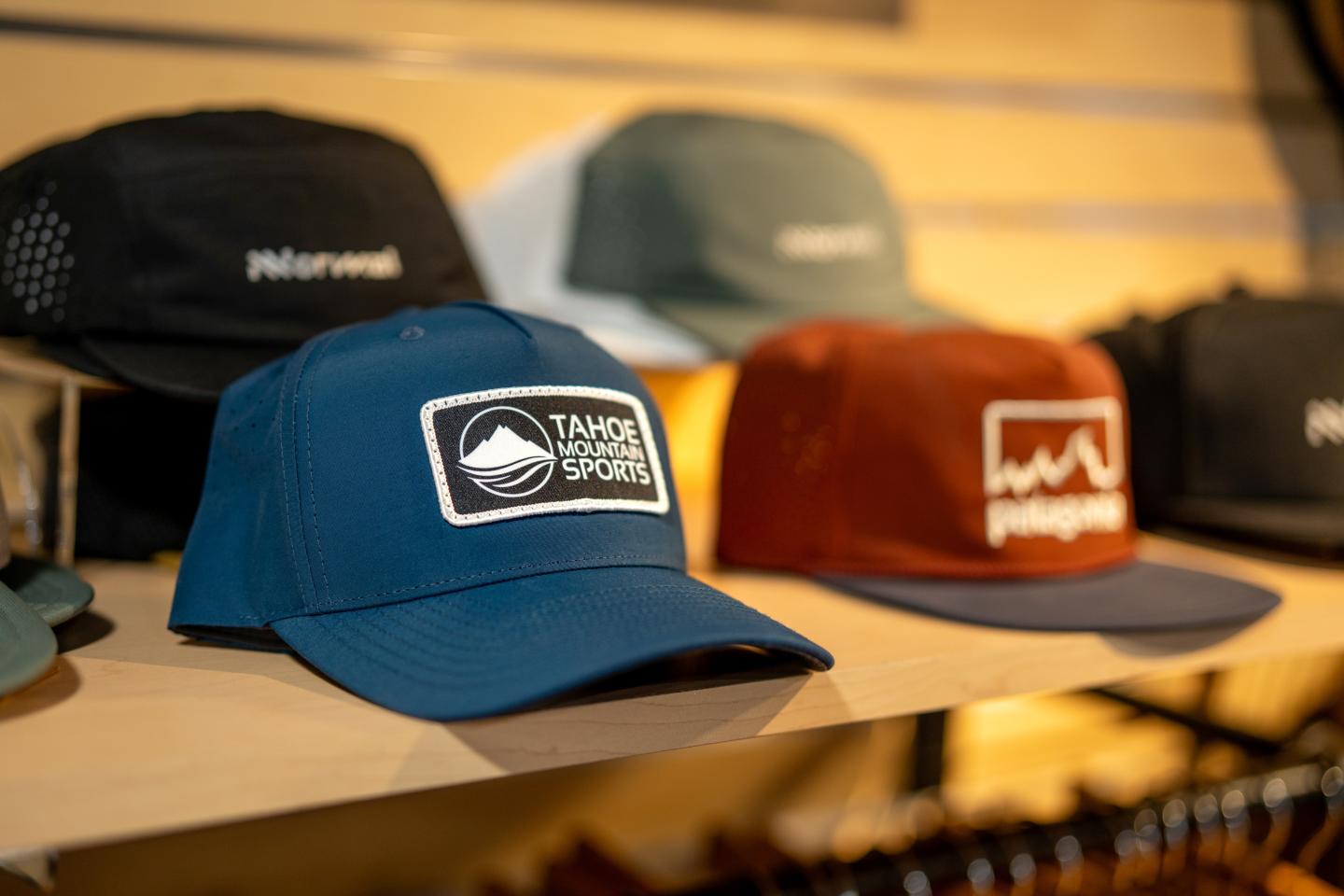 Caps displayed on a shelf, featuring various colors and logos.