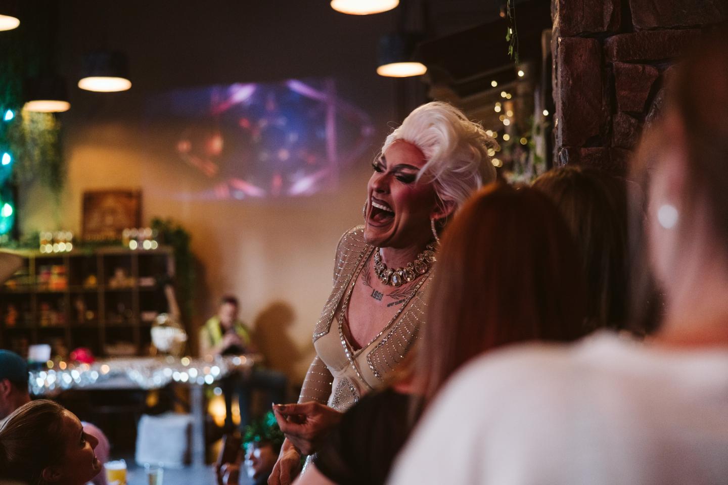 Drag performer in a lively bar, engaging with an audience.