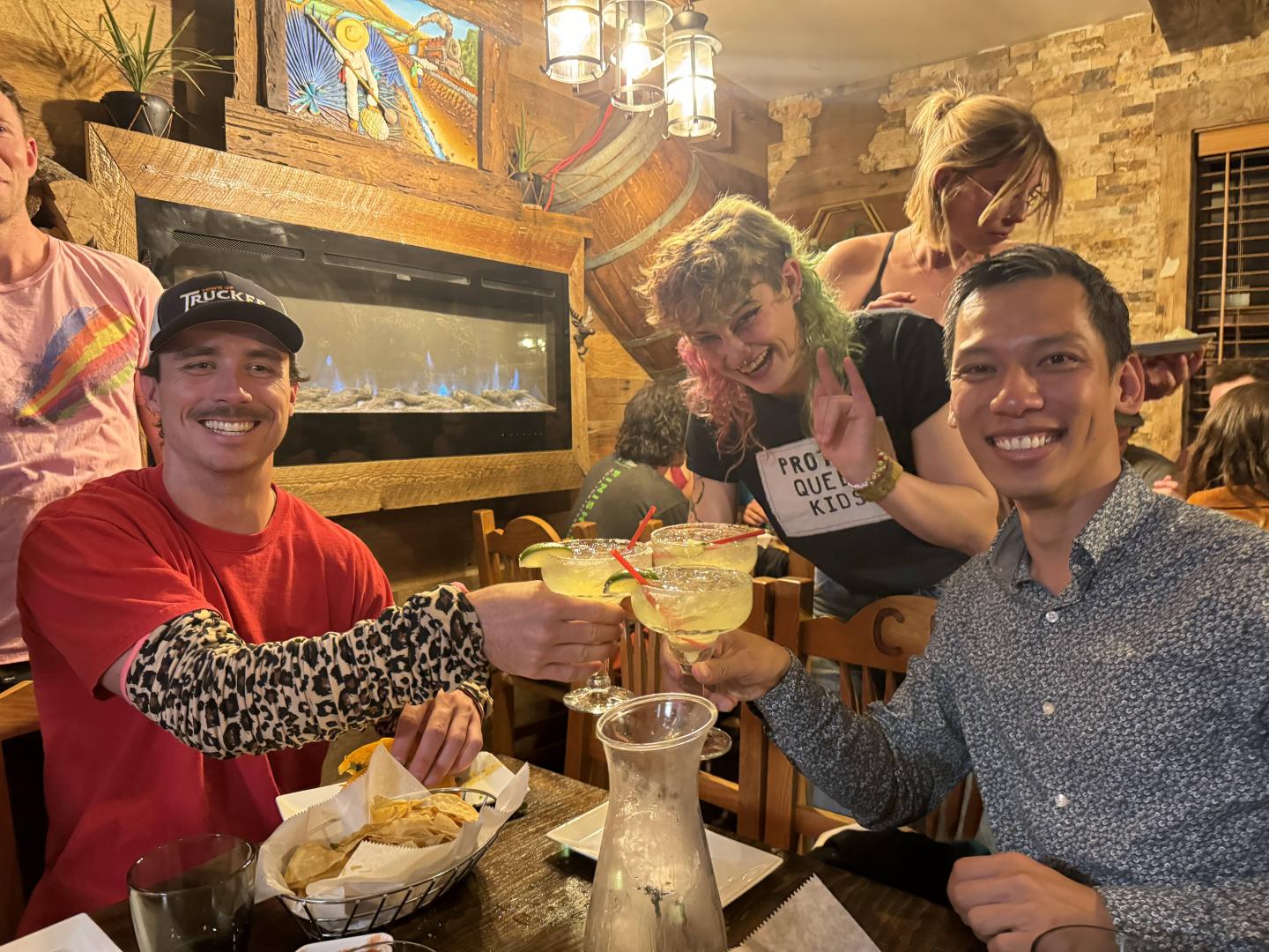 Friends toasting margaritas in a cozy restaurant setting.