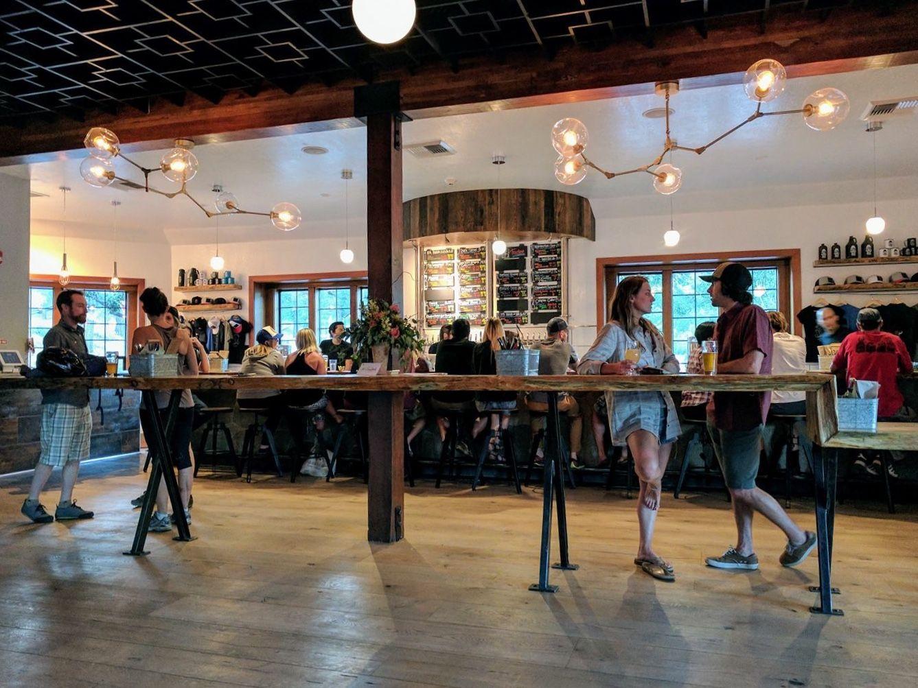 A lively café with people chatting, a long wooden bar, and warm lighting.