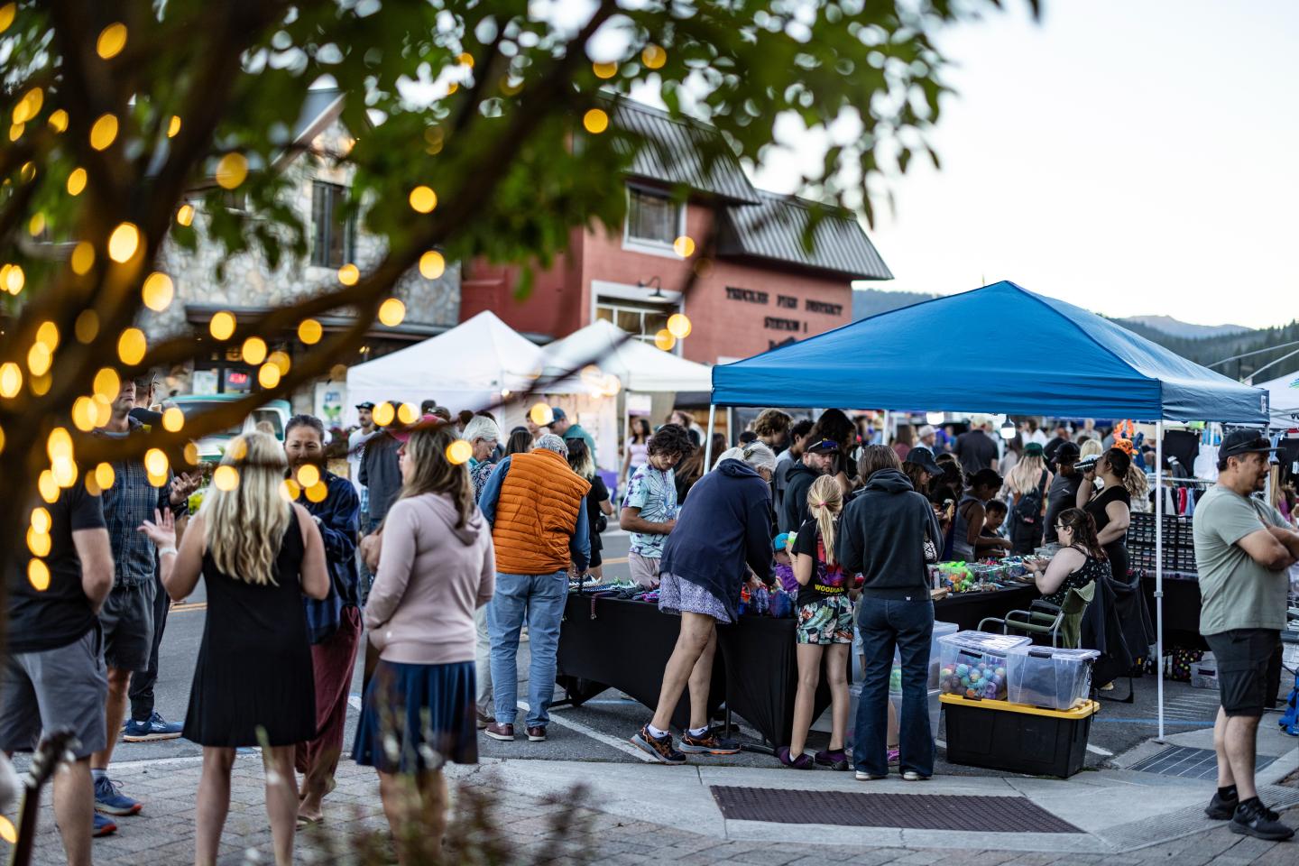 Outdoor market with people gathered under tents at dusk.