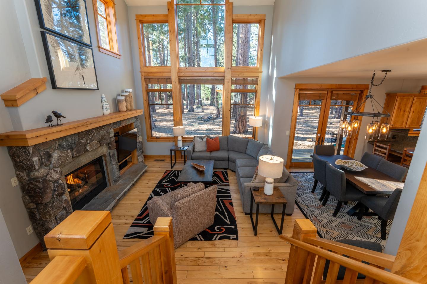 Cozy living room with a fireplace, large windows, and forest view.