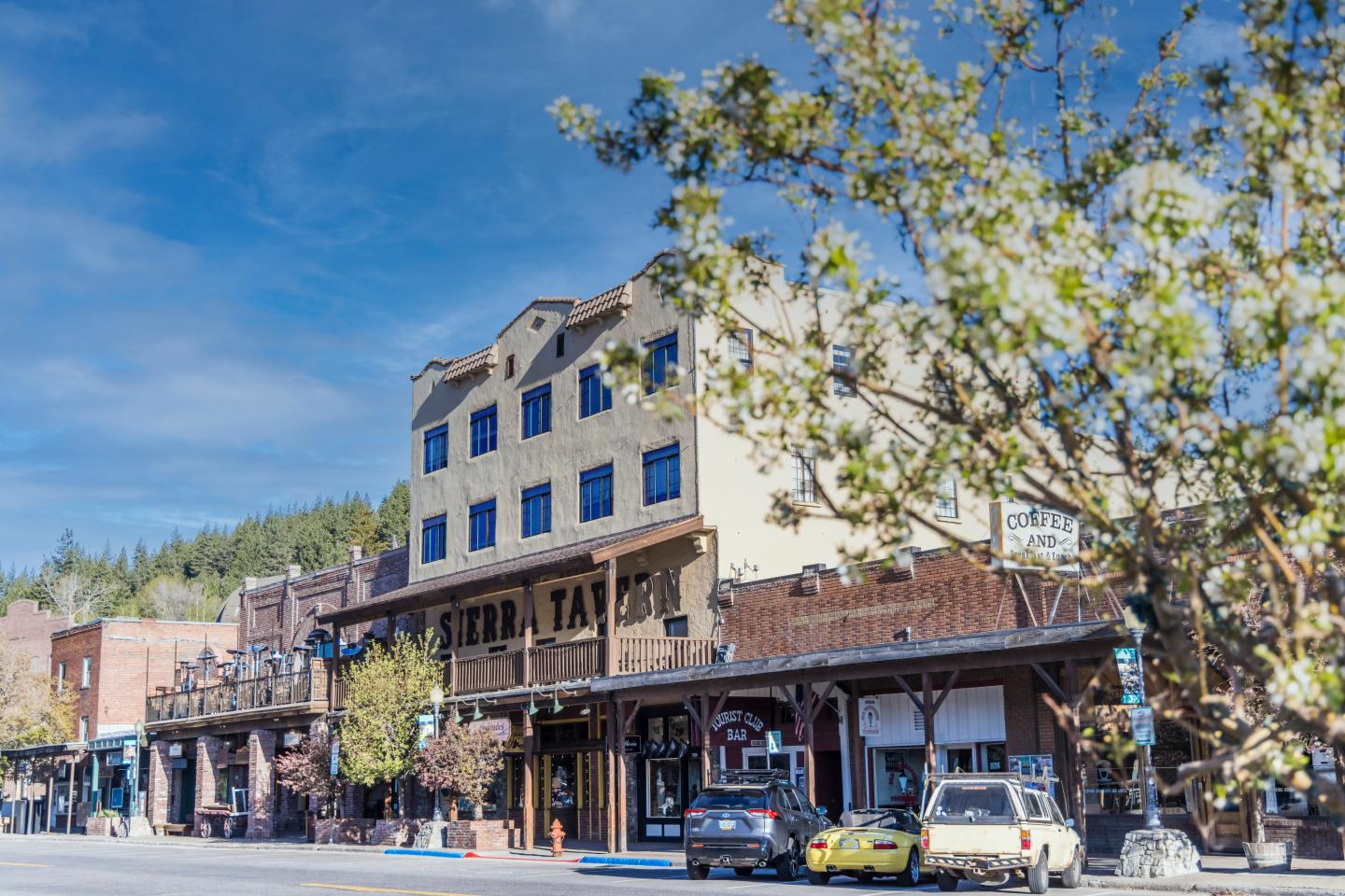 Historic downtown street with shops and parked cars under a blue sky.