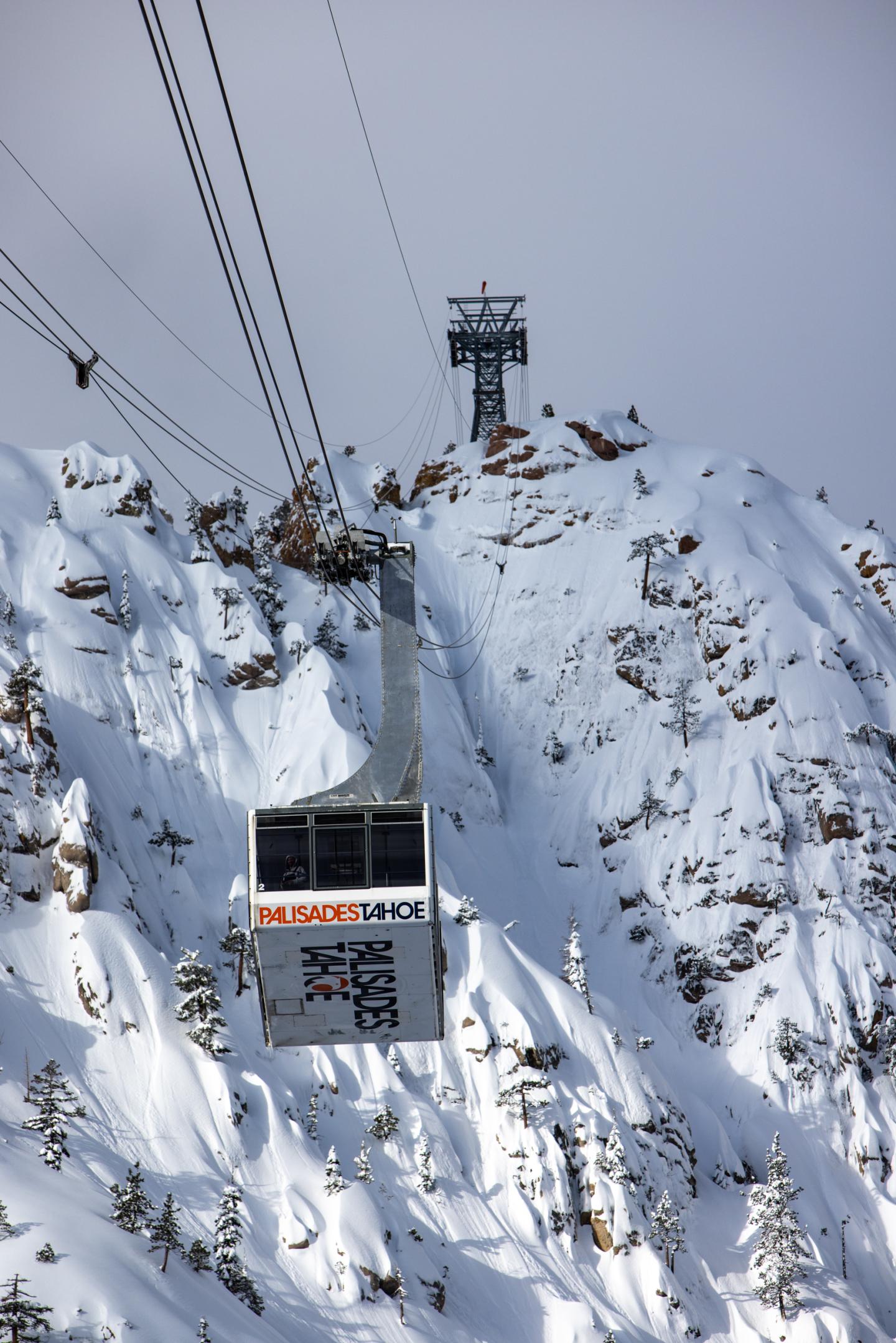 Aerial tramway ascending snowy mountain.