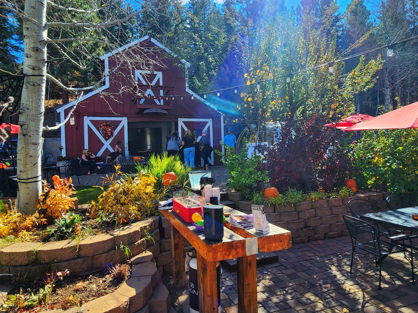 Red barn in sunny garden with flowers and patio furniture.