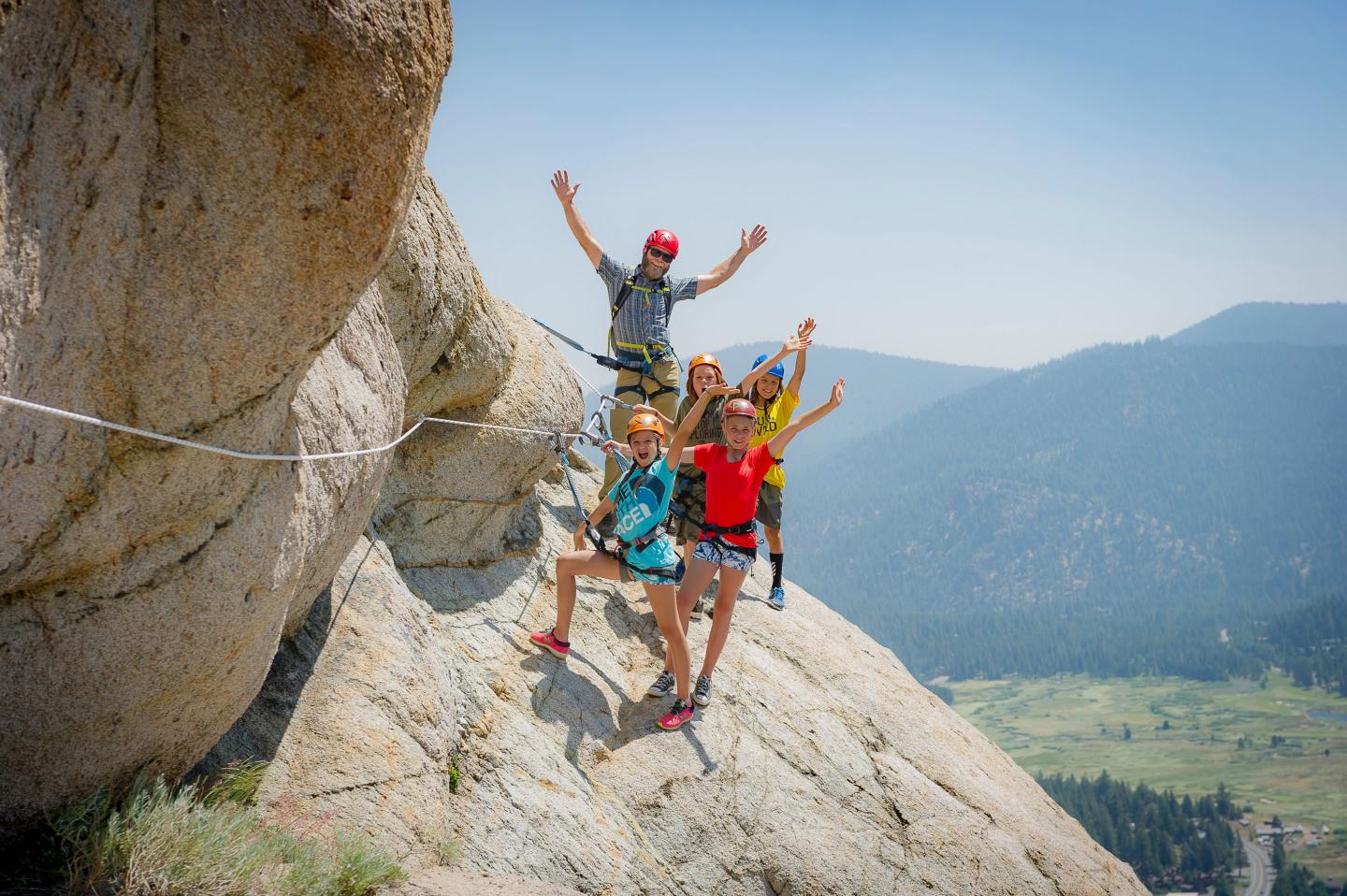 Group of climbers cheering on rocky mountain cliff.