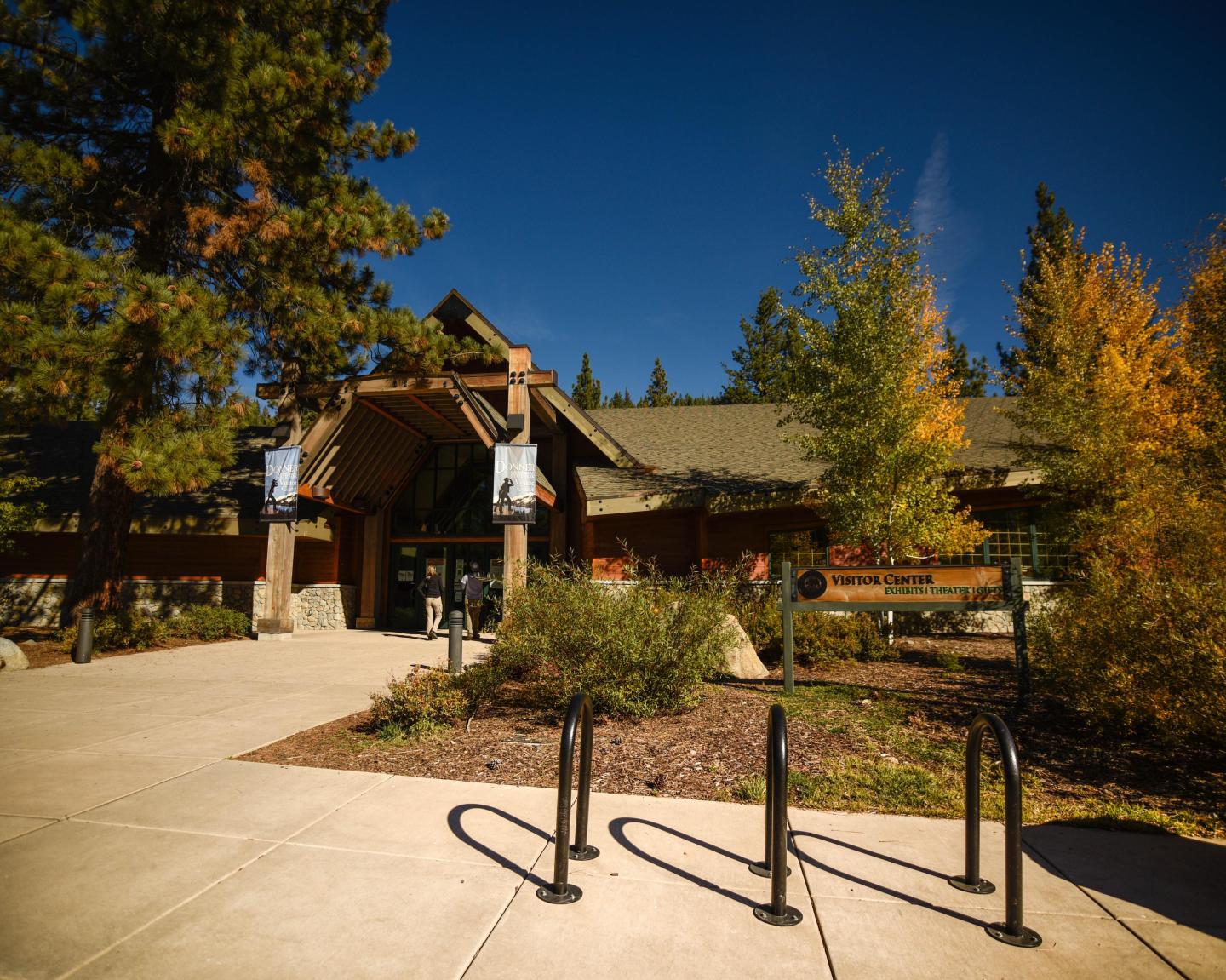 Visitor center entrance surrounded by autumn trees under a clear blue sky.