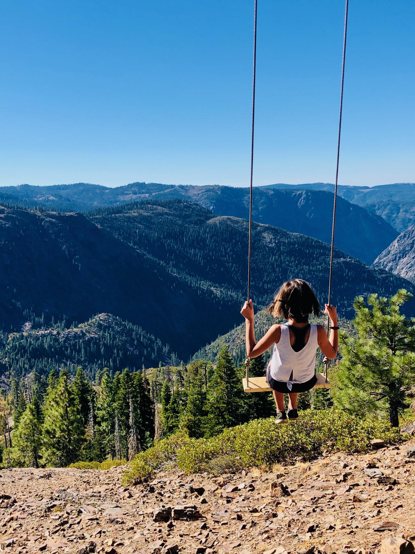 Person swinging with a mountainous landscape in the background.