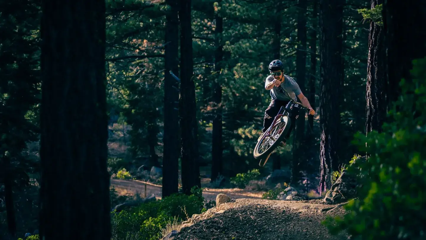 Cyclist jumping on a mountain bike trail in a forest.