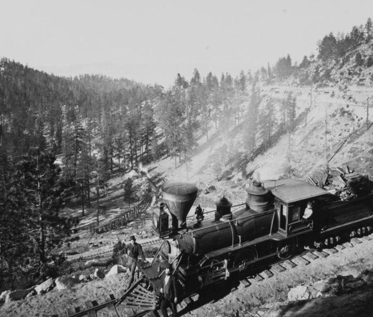 Steam train on a mountain railway through a forested valley.