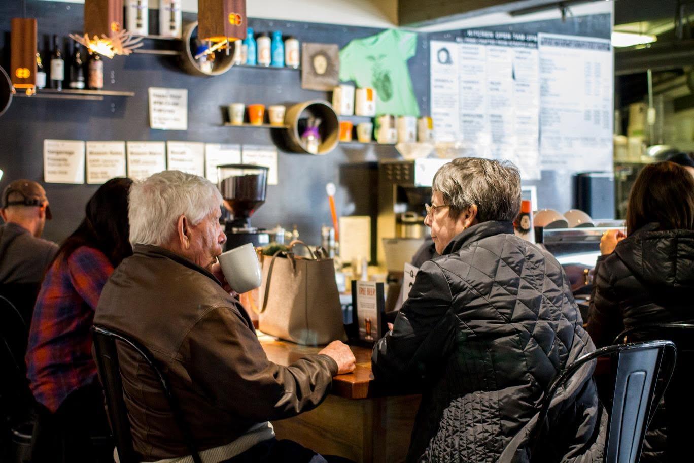 Café interior with people sitting at a counter, chatting and drinking.