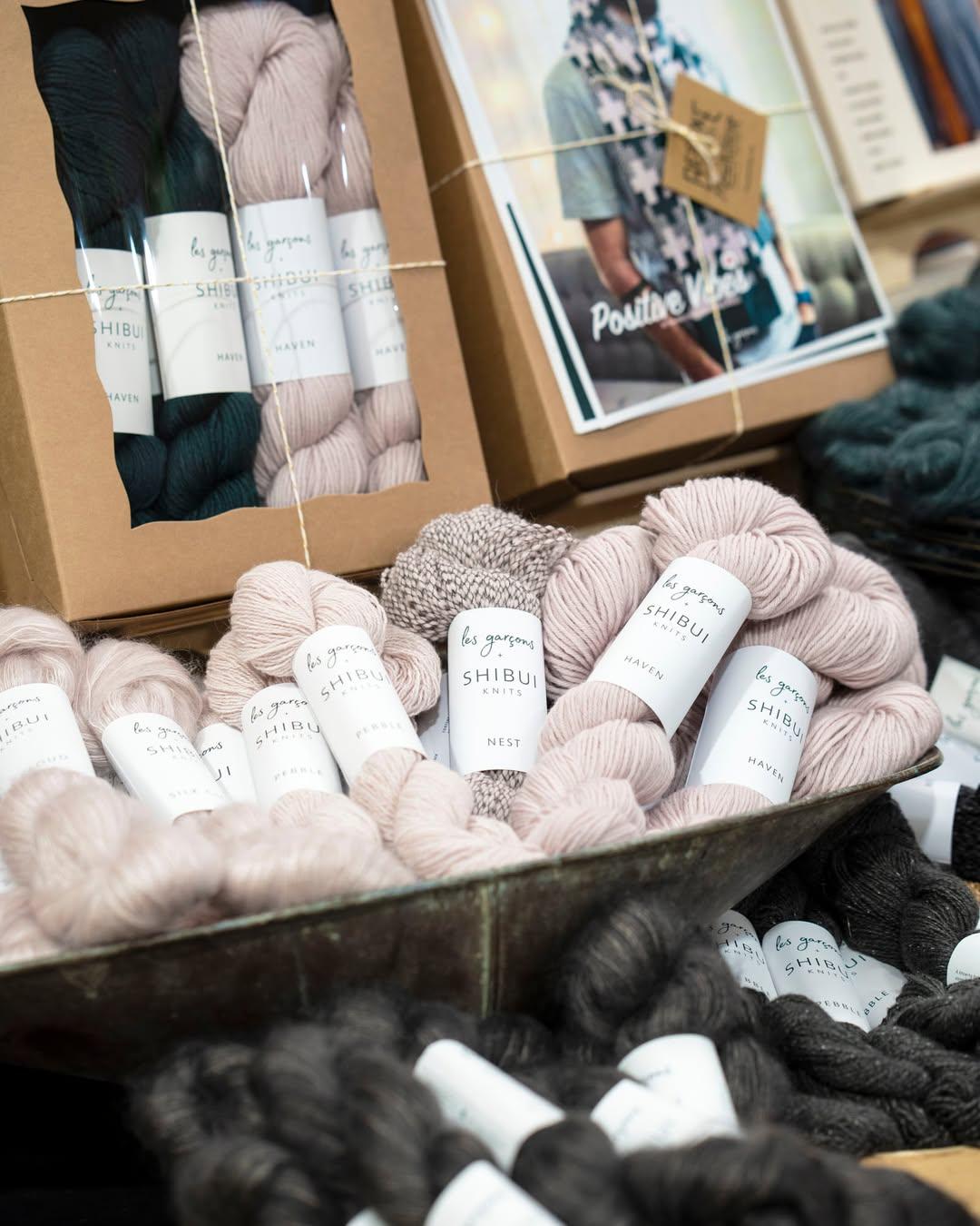 Skeins of pastel and dark yarn in a display basket.