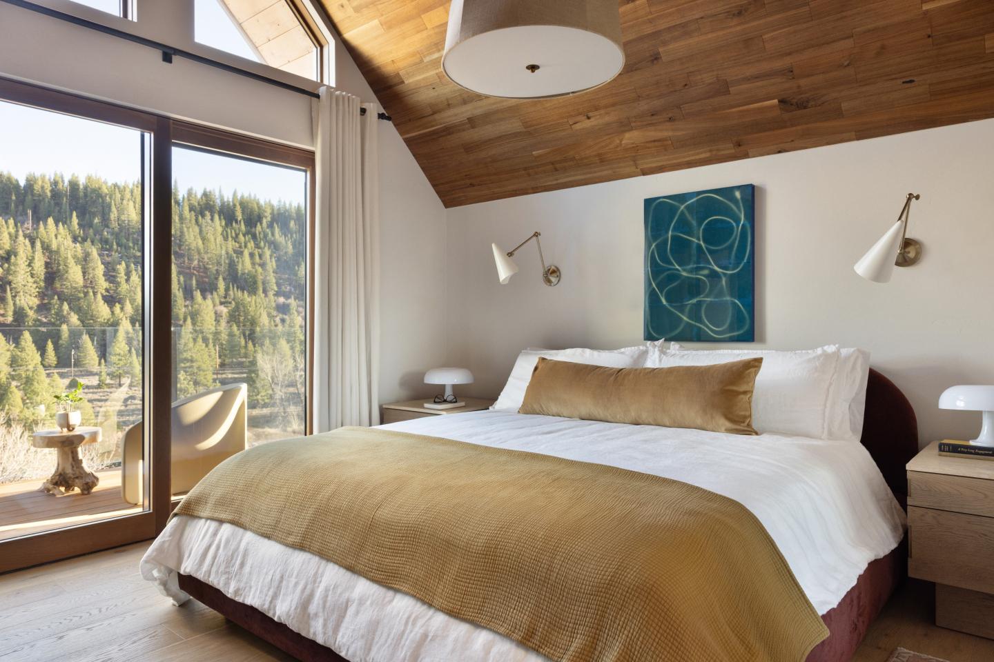 Cozy bedroom with large bed, forest view, and modern decor.