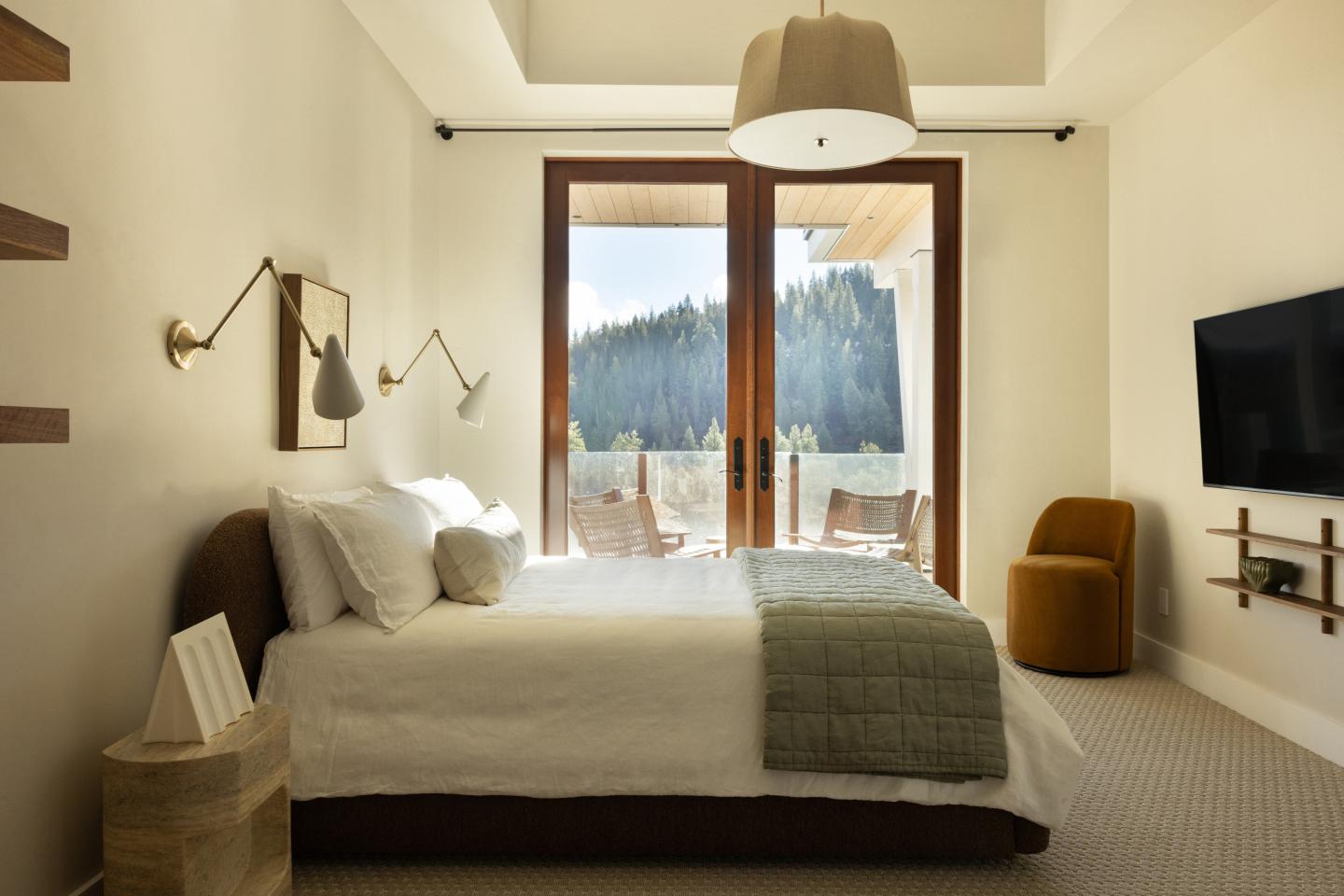 Modern bedroom with large window, mountain view, and neutral decor.