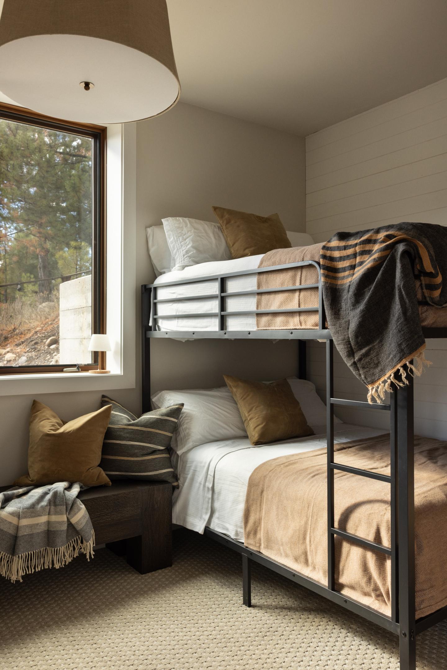Cozy room with bunk beds, neutral tones, and a large window with a tree view.