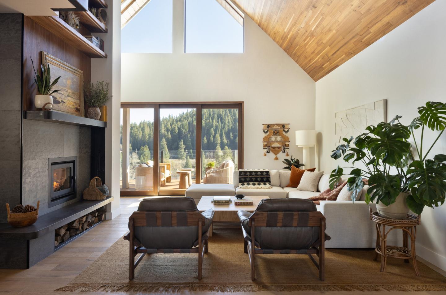 Spacious living room with large windows, plants, and a cozy fireplace.