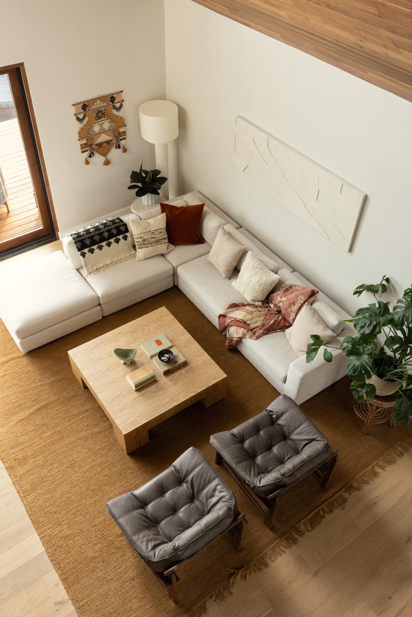 Cozy living room with a white sectional, cushions, coffee table, and plants.