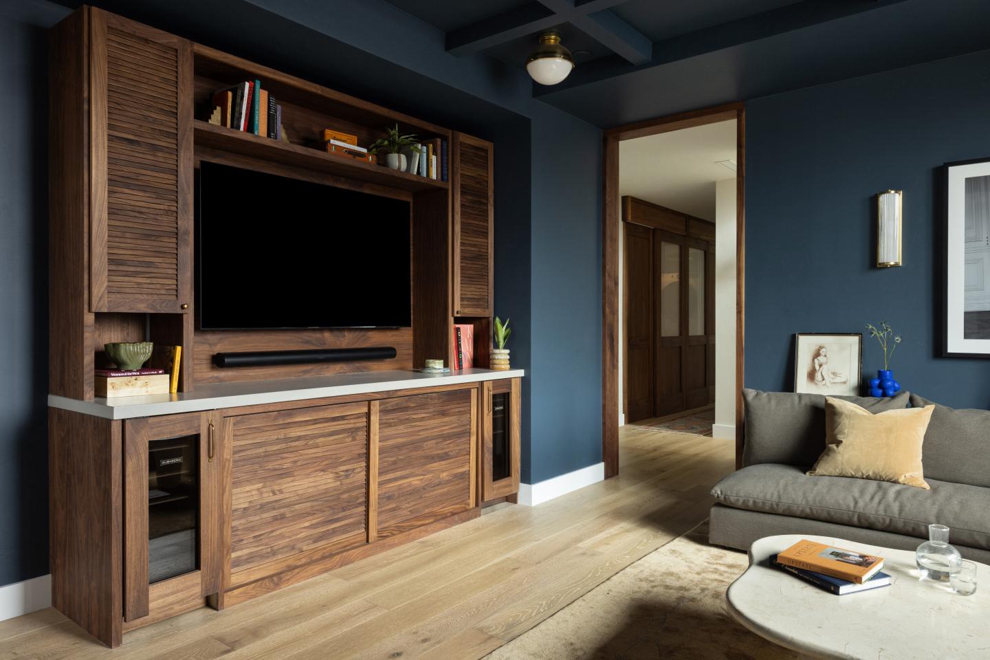 Cozy living room with dark blue walls and a wooden TV cabinet.