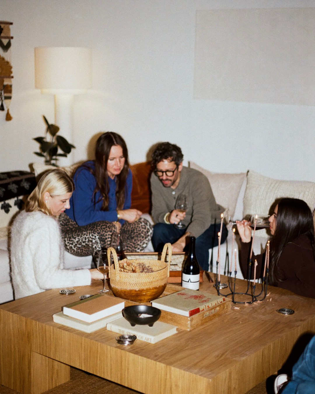 Four friends gathered around a wooden table, chatting and sharing wine.