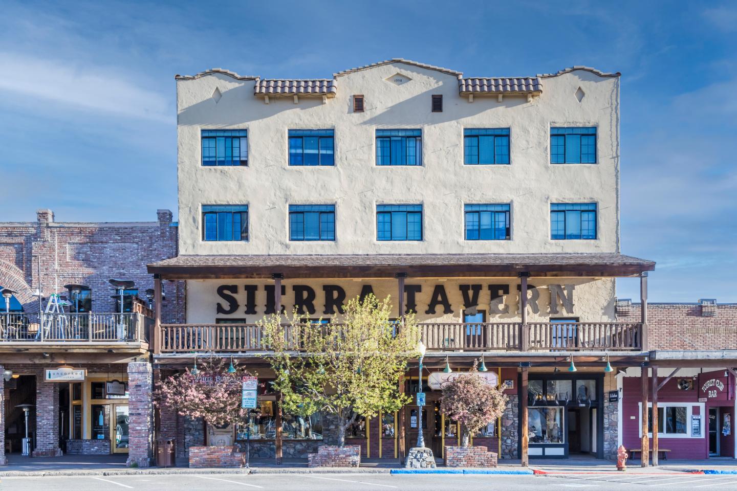 Sierra Madre storefronts beneath a white, blue-windowed historic building.