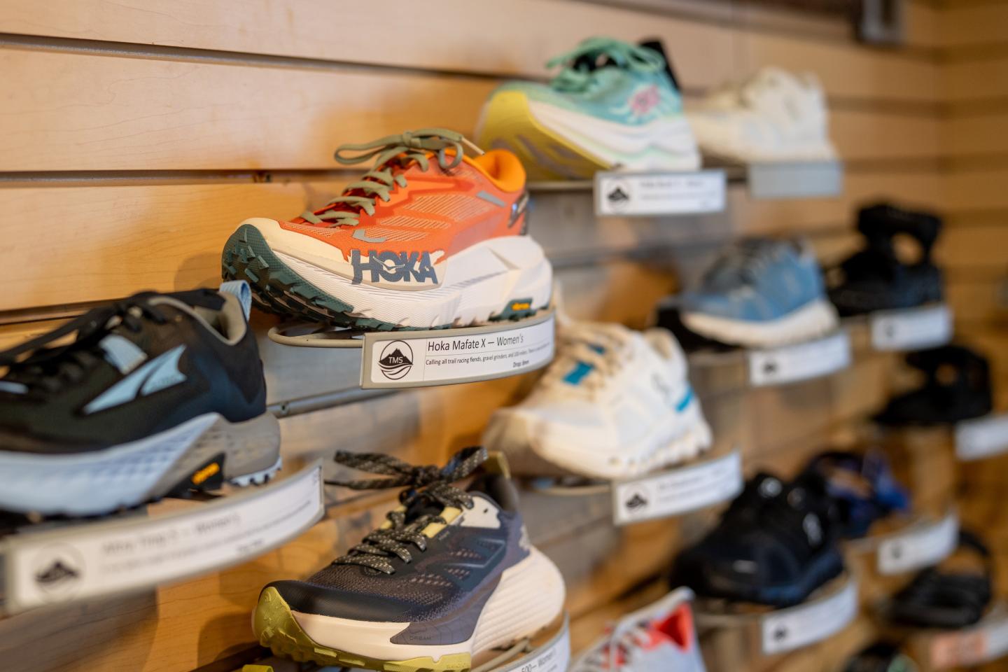 Colorful athletic shoes displayed on wooden wall shelves.