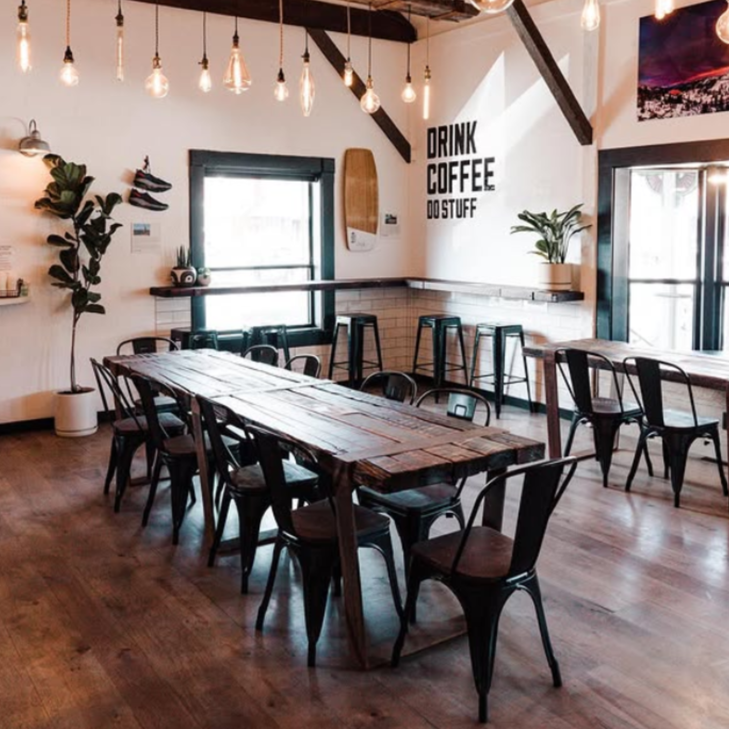 Rustic café interior with a long wooden communal table and black chairs.