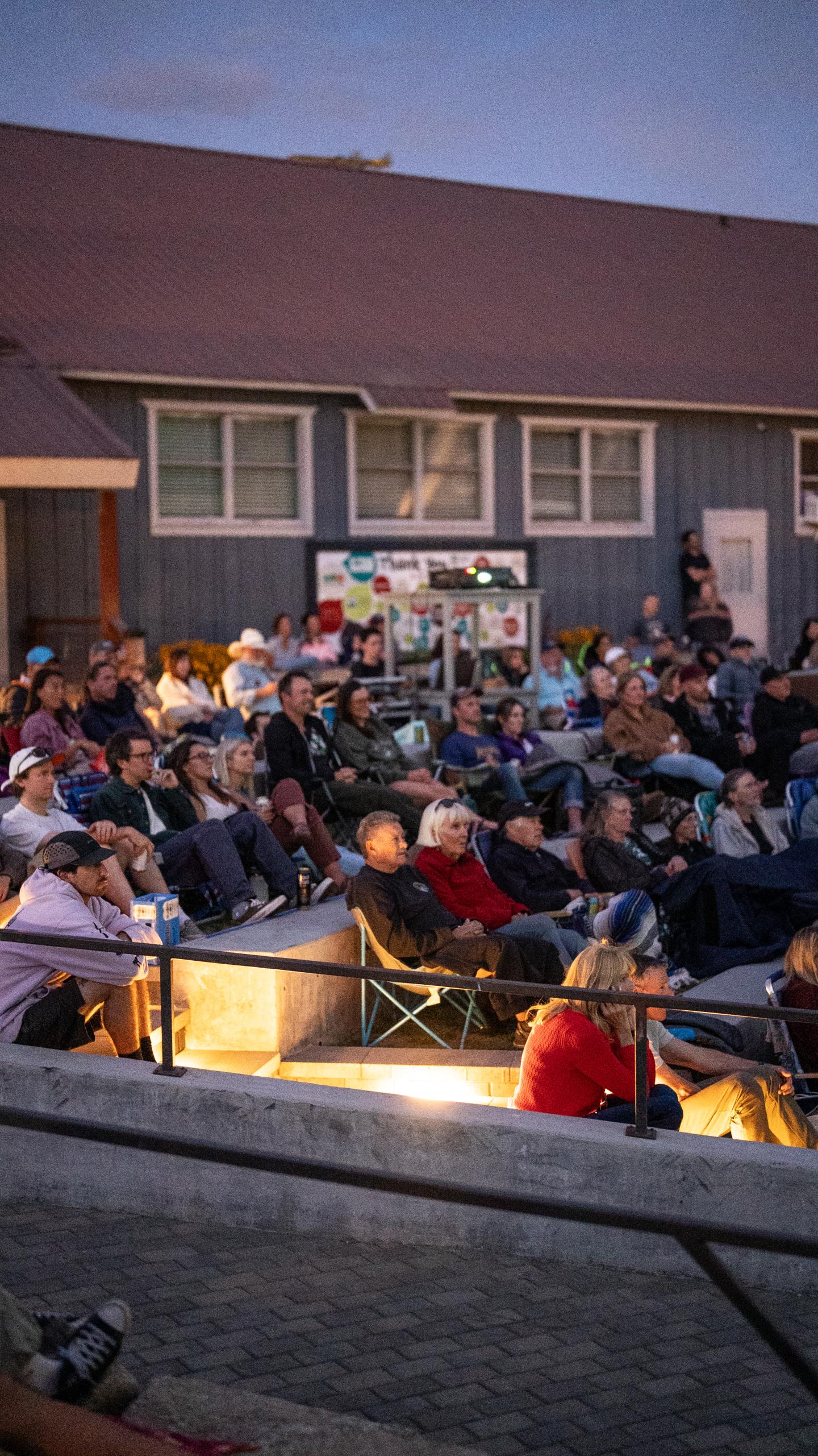 Crowd gathered on a patio outside a house at dusk.