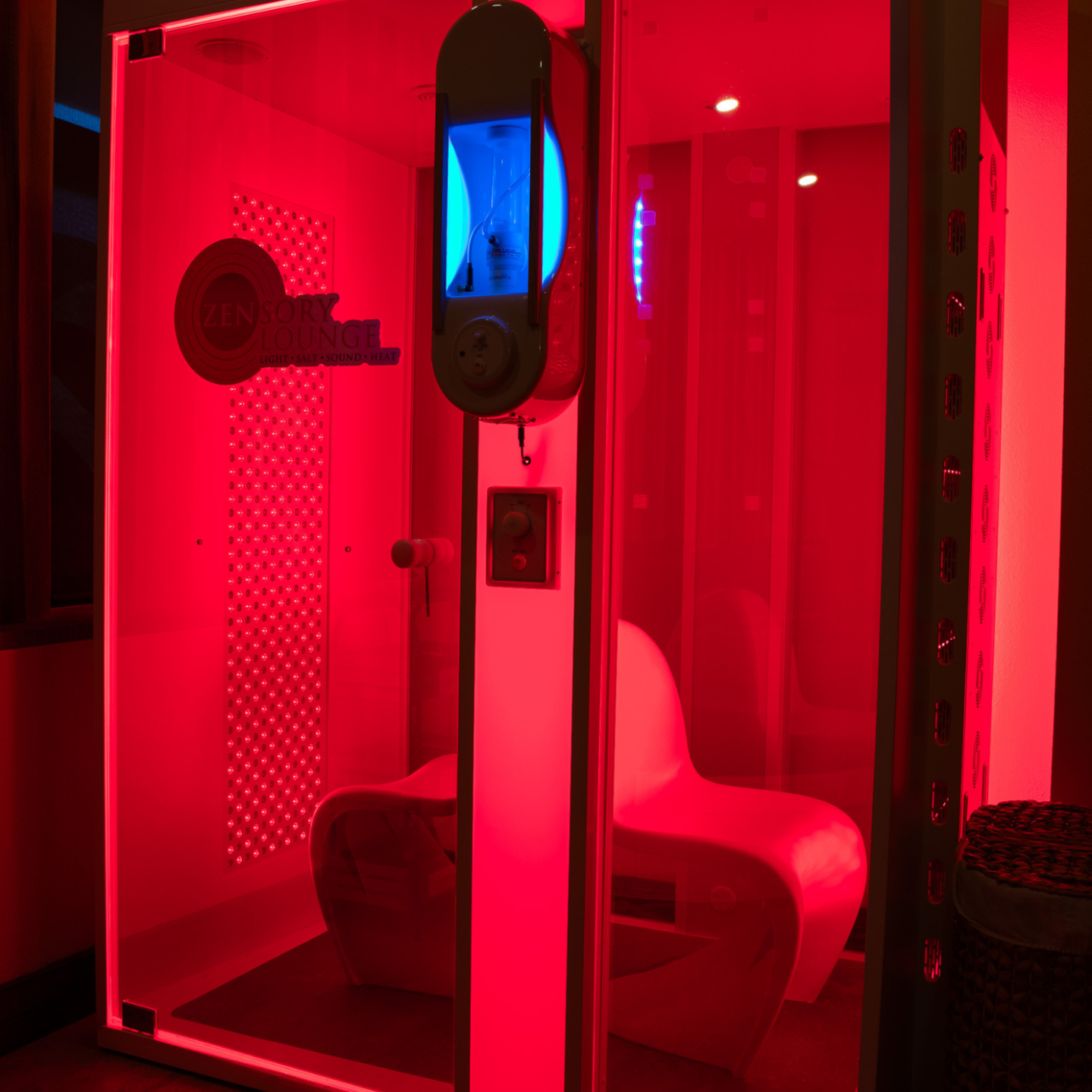 Red-lit futuristic booth with a white chair and circular wall fixture.