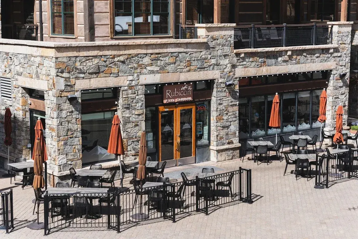 Outdoor patio seating at a rustic stone restaurant with orange umbrellas.