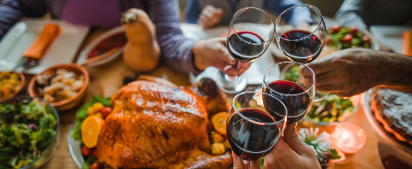 Festive dinner table with roast turkey, wine glasses, and holiday decorations