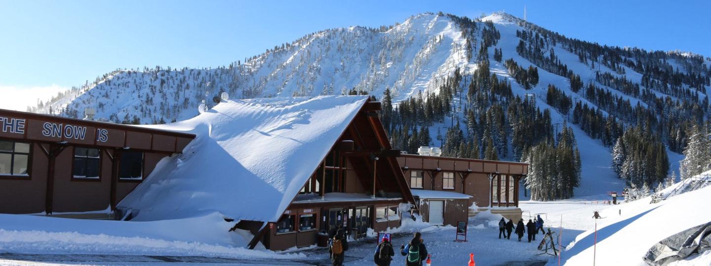 Snow-covered mountain lodge beneath rugged alpine peaks.