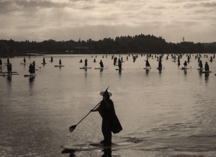 Sepia photograph of people ice skating on a frozen lake at sunset.